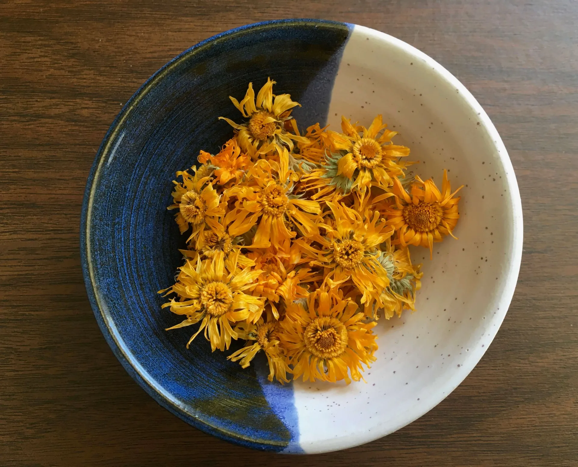 Yellow dried calendula flowers in a blue and white bowl
