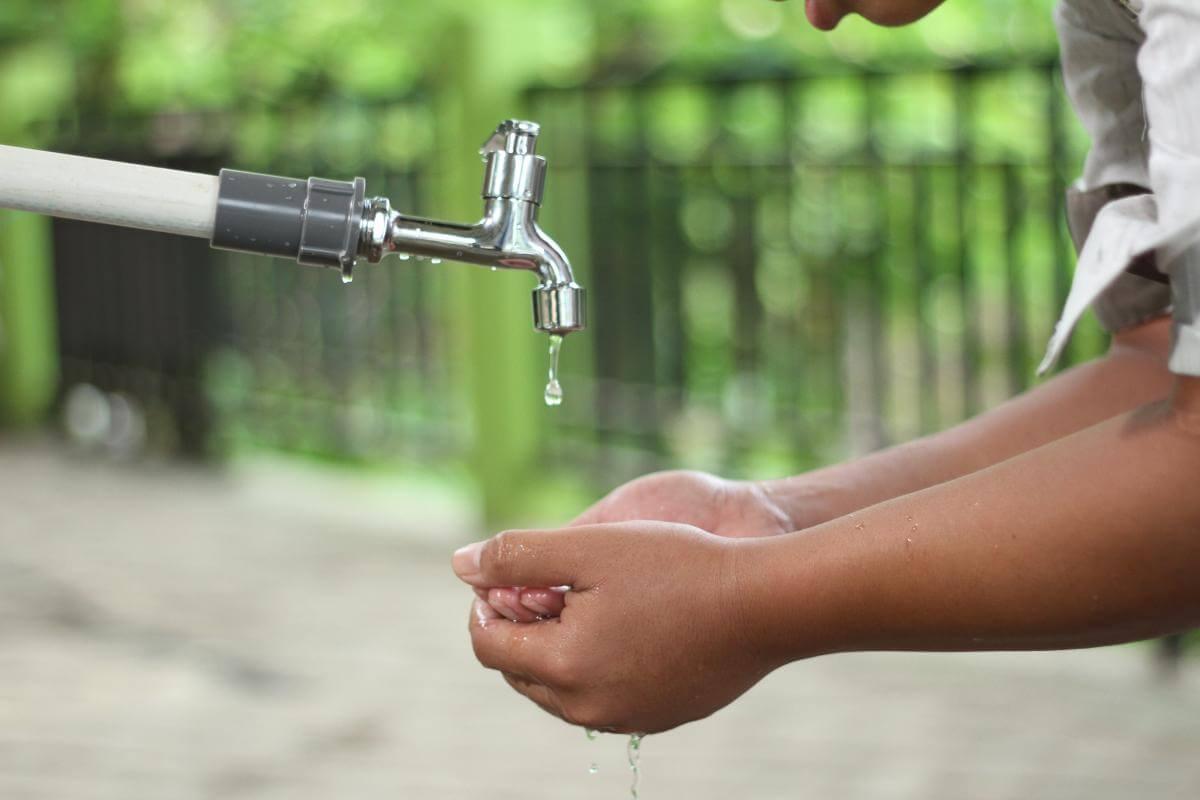 Person washing their hands in an open faucet