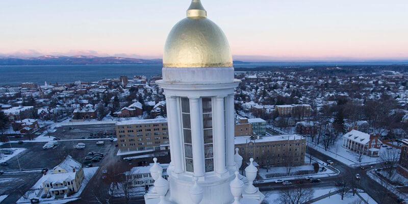 The dome of Ira Allen with Burlington in distance via drone