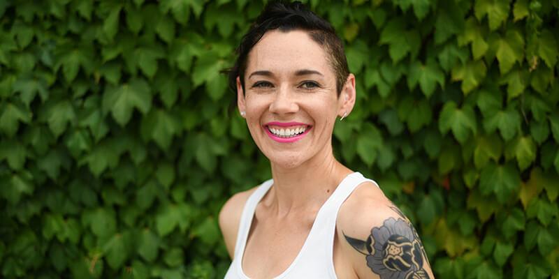 UVM alumna Meg Little Reilly smiles in front of ivy-covered wall