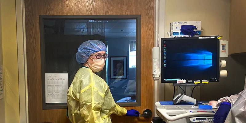 Megan O'Brien in a hospital room in gown and mask