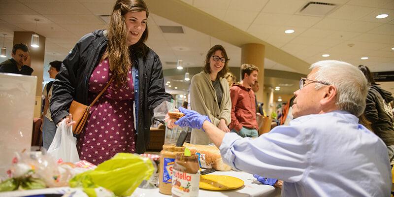 Dr. Harry Chen hands University of Vermont student a sandwich