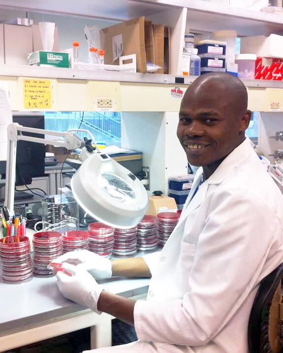 Robert Mugabi working in a lab with a microscope