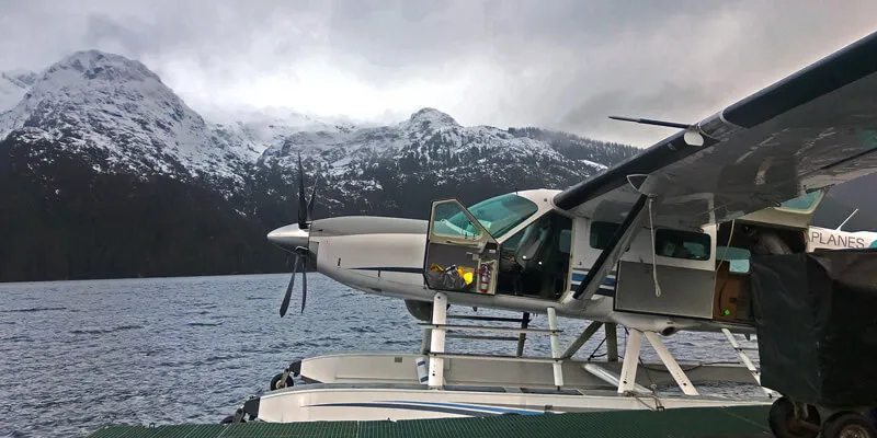 Sea plane docked beside snow-capped mountains in Alaska