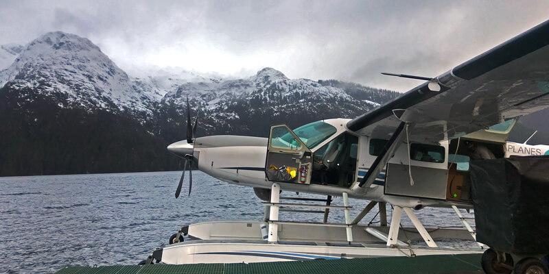 Sea plane docked beside snow-capped mountains in Alaska