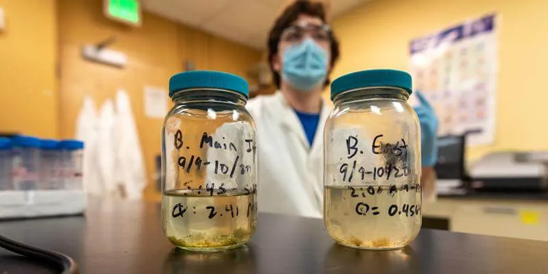 Ben Page displays two samples of wastewater in a science lab