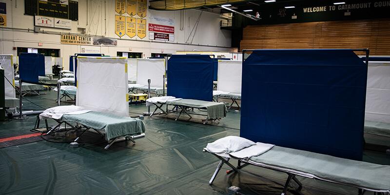 Rows of cots and screens in the surge hospital space set up in Patrick Gym
