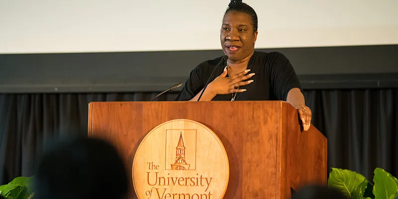 Tarana Burke speaks at a podium at the University of Vermont