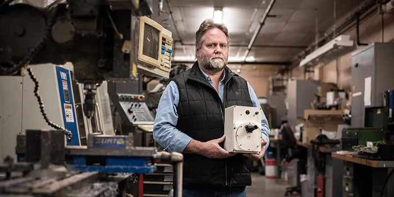 Carl B. Silver  holds a prototype of a ventilator in a lab 