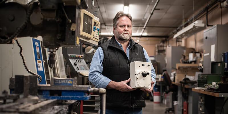 Carl B. Silver  holds a prototype of a ventilator in a lab 