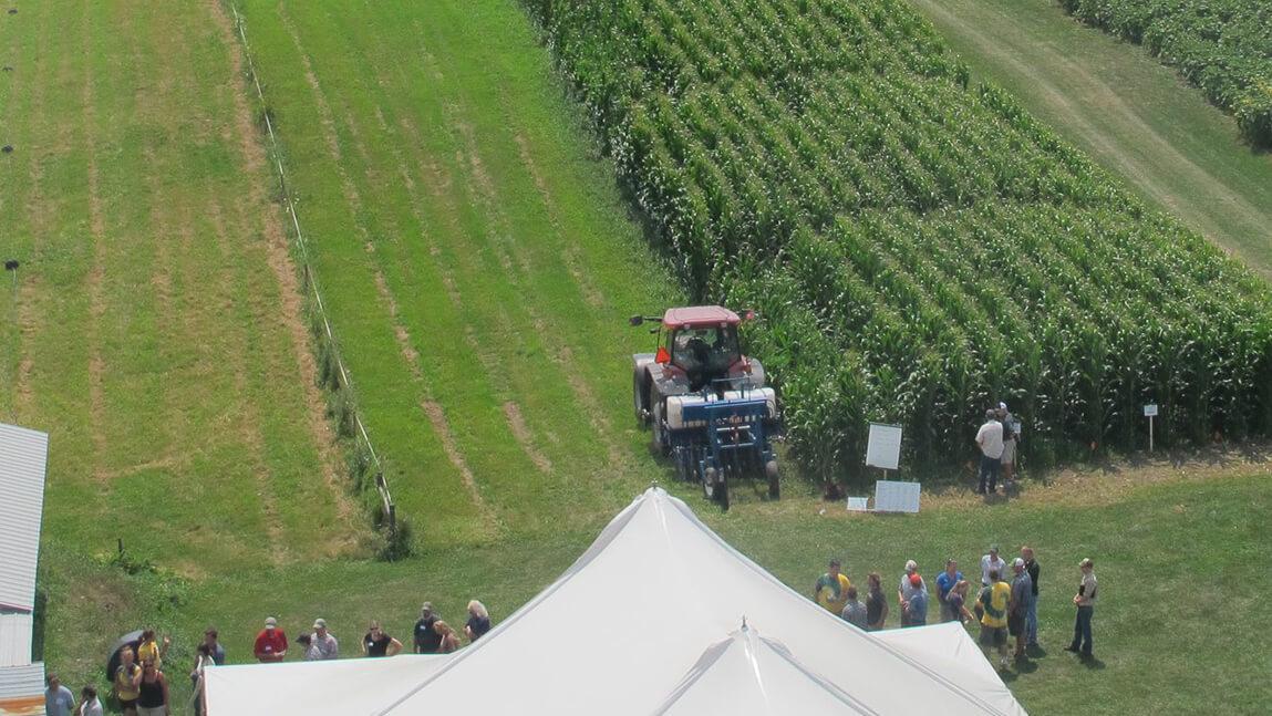 aerial photo of farm fields and tractor viewed by crowd