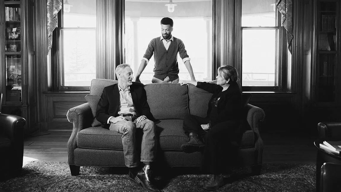 three faculty members have a conversation in a library