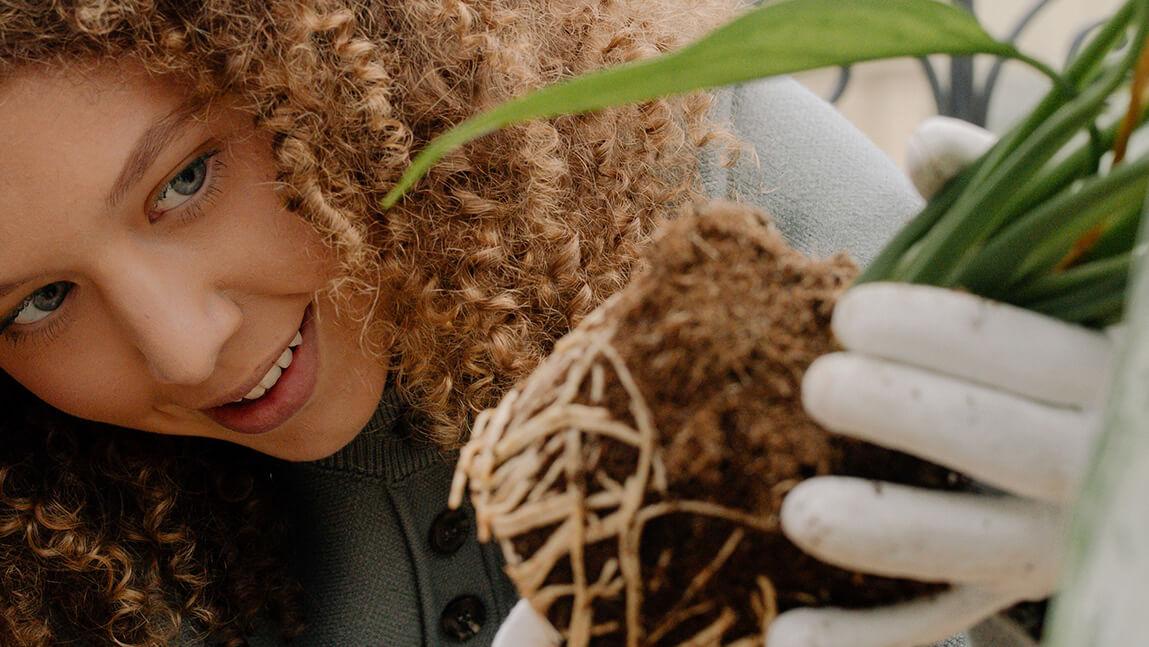 young woman looking at the roots of a small plant