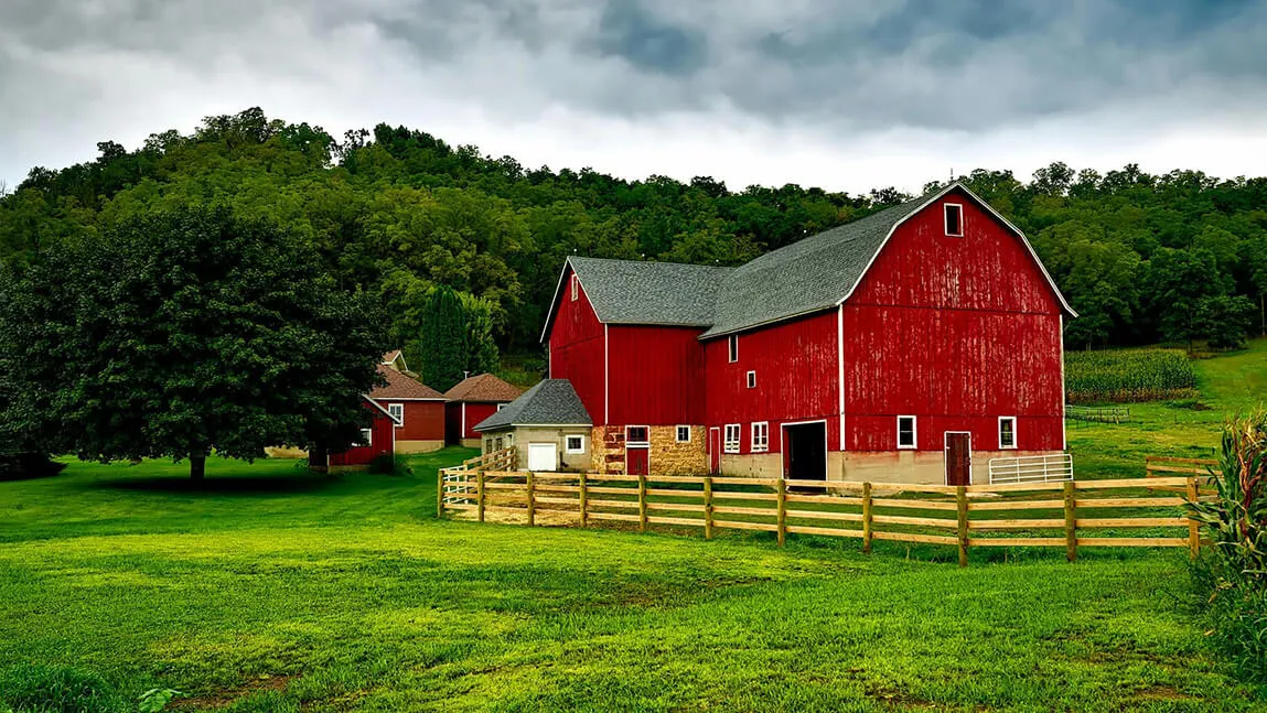 red barn with hills in the background and grass out front