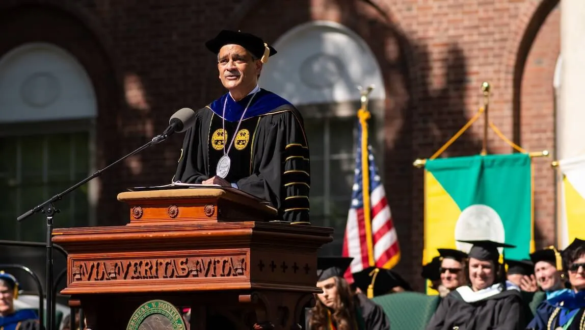 View of President Garimella speaking at podium in front of the Waterman Building