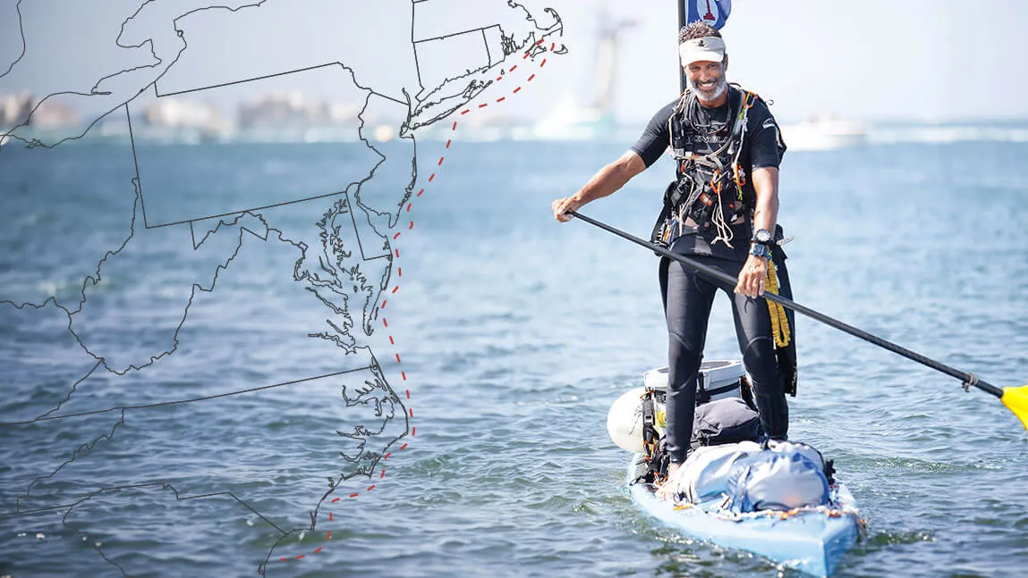 adam nagler stands on a paddle board in the middle of the ocean