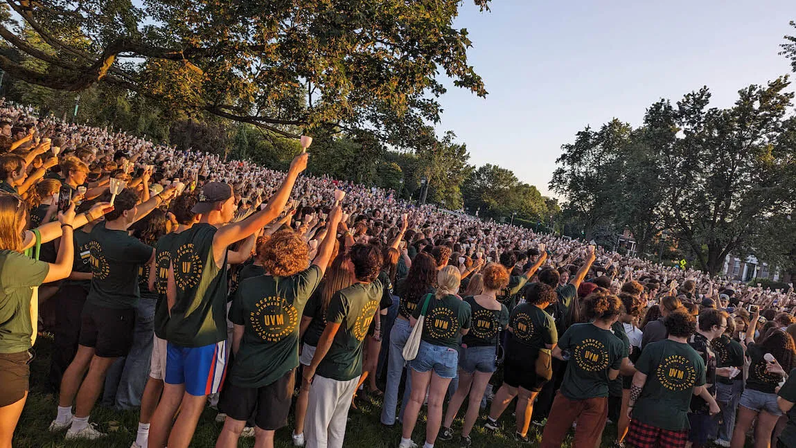 UVM Class of 2027 students holding up candles on the Green during Convocation.