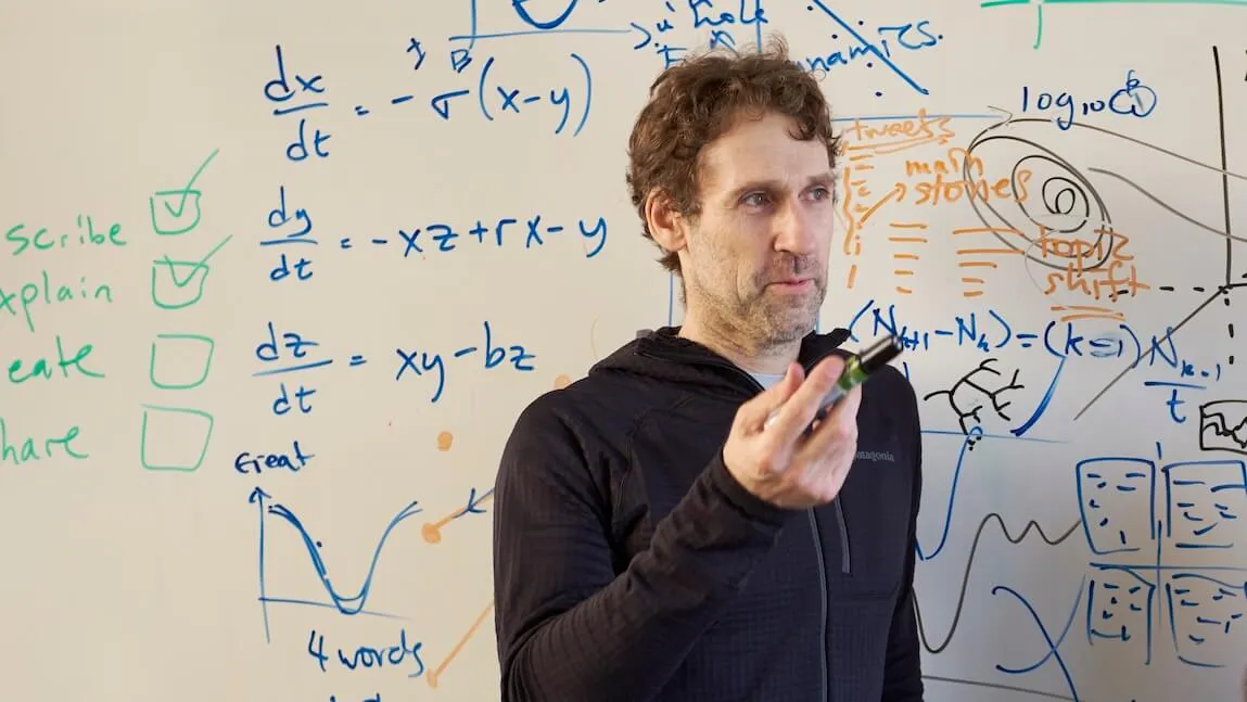 Peter Dodds stands in front of a whiteboard