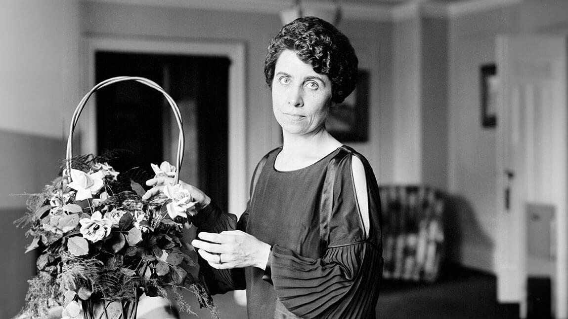 A black and white photo of Grace Goodhue Coolidge arranging flowers