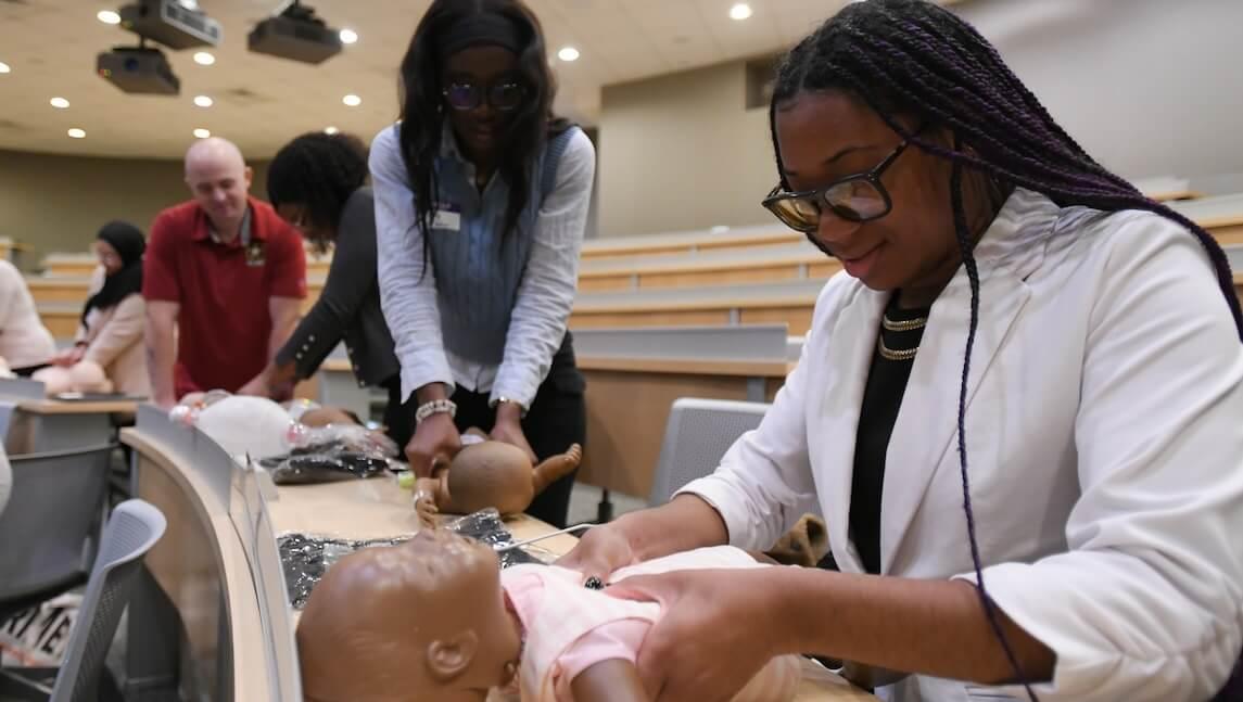 Medical students working with a manikin of a baby.