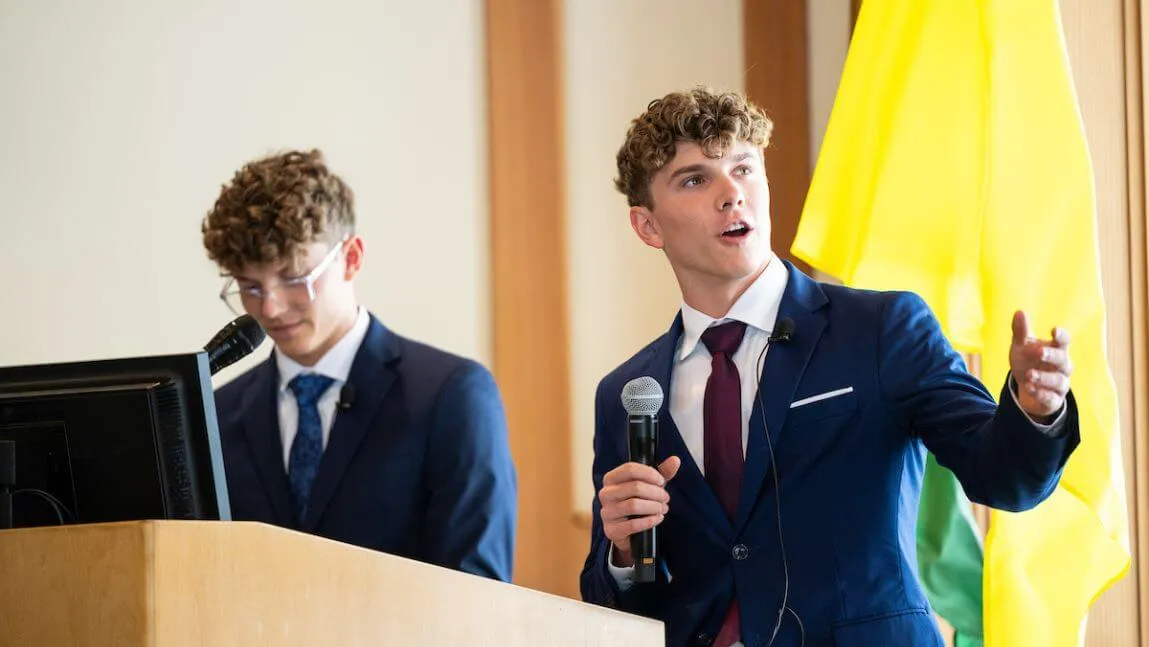 Two students wearing suits give a presentation 