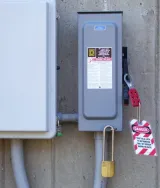 Red and white lockout tagout tag hanging from a utility box