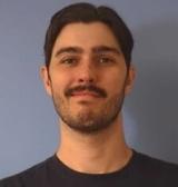 A man with black hair and moustache wearing a black shirt