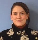 A woman with brown hair wearing a black and white sweater 
