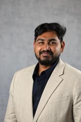 A man wearing a tan suit and black shirt