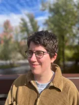 A woman with dark brown hair and a mustard colored sweater