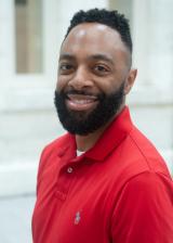 A man with black hair and a black beard wearing a red shirt