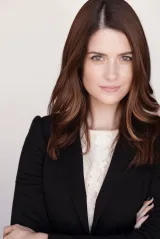 A woman with red hair wearing a suit 