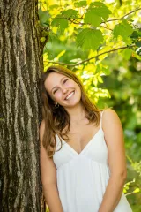 Undergraduate student leaning against a tree