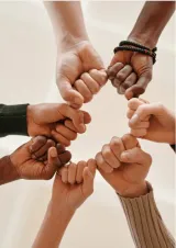 fists in a circle, photographed from below, a collective fist bump