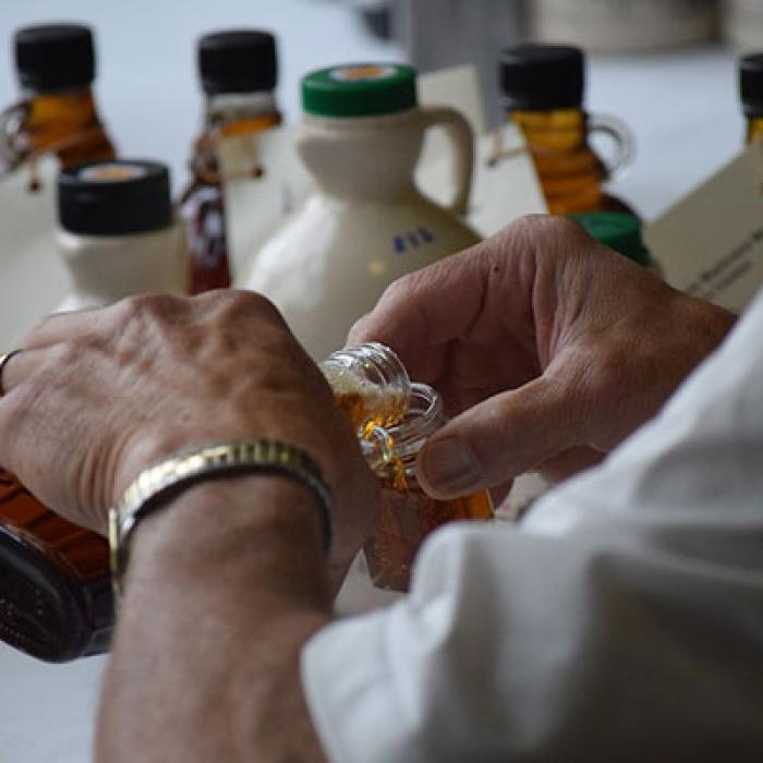 Person pouring maple syrup into a jar