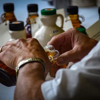 a person pouring maple into a jar