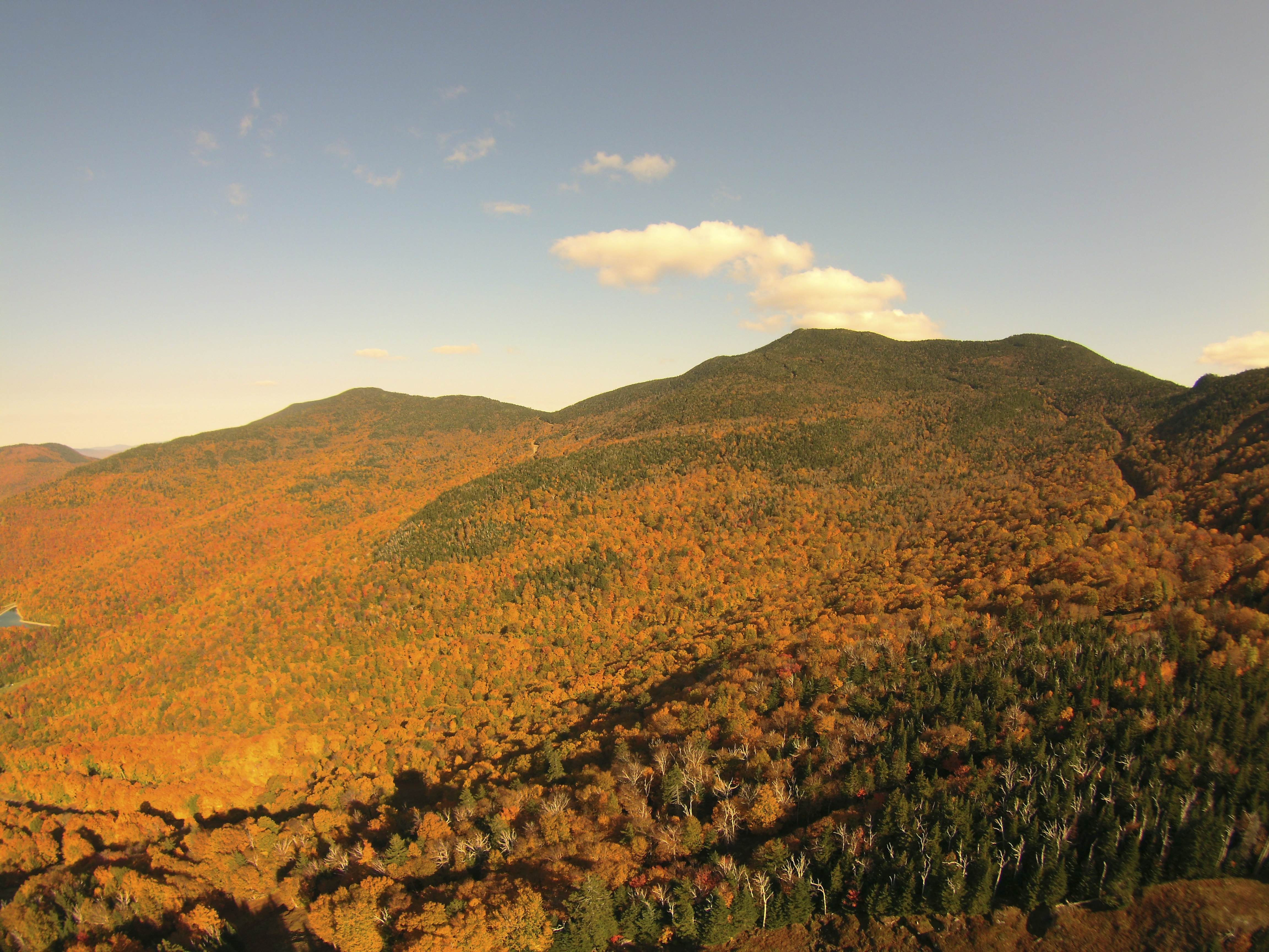 Photo of Vermont mountain with autumn leaves lit up in golden sun.