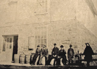 Grist mill workers standing outside mill