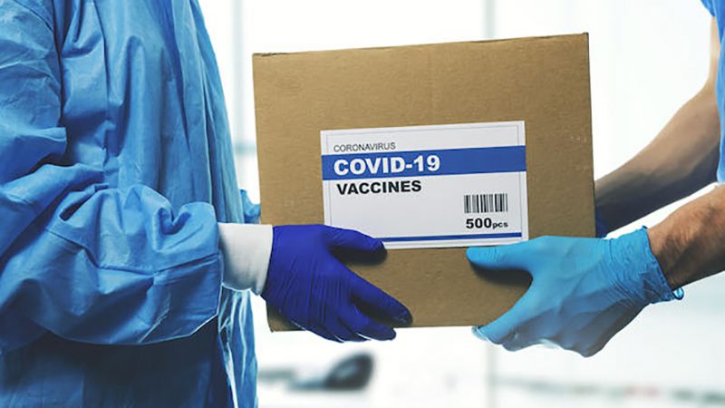 medical worker accepting delivery of covid-19 vaccines from deliveryman