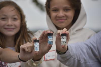 Students holding containers of different types of plastic