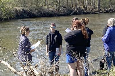 Watershed Alliance intern teaches a group of high school students near a river.