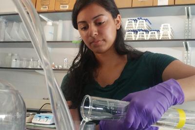Nisha pours liquid into a funnel in laboratory