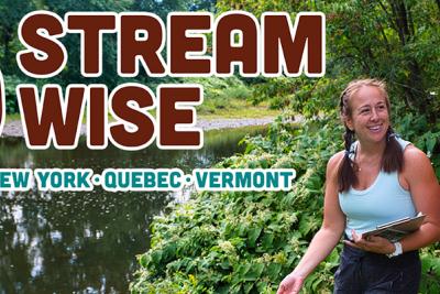 Two women talking next to forested stream.