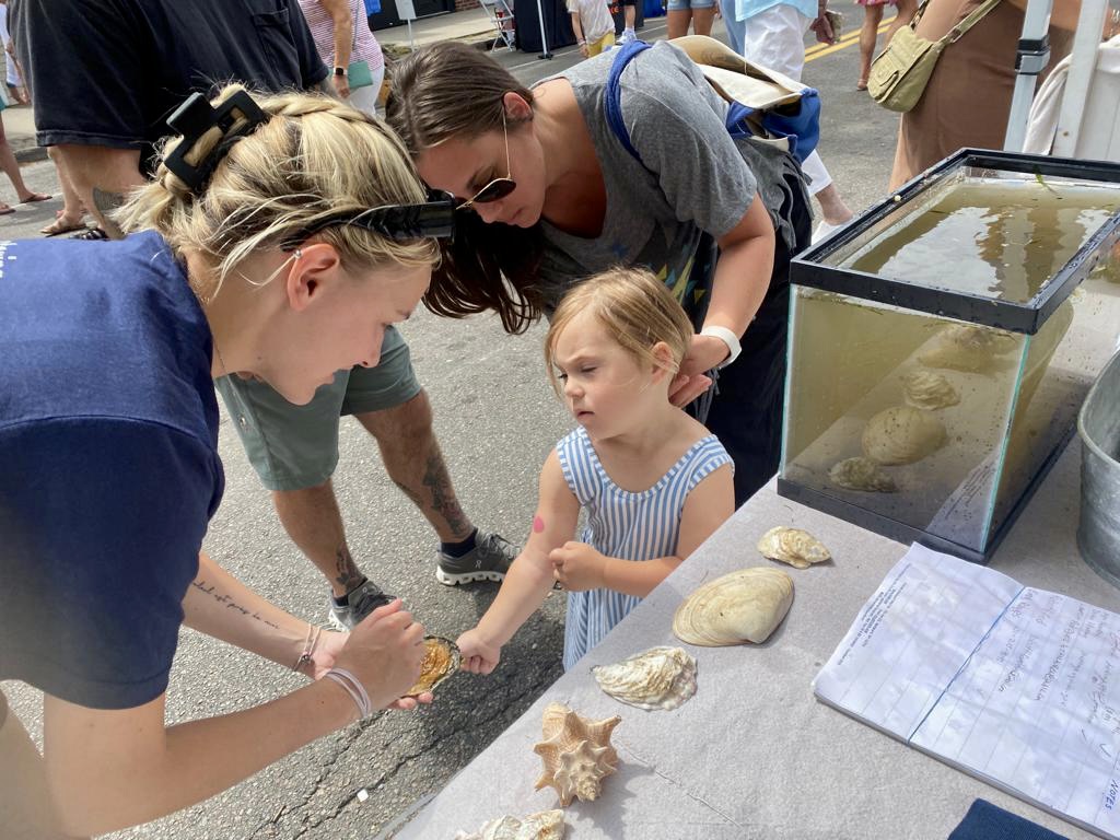 Frania Darringer showing a girl how to hold an oyster