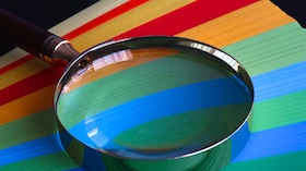 A magnifying glass enlarges the details of a painted rainbow