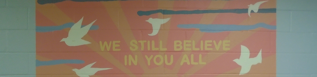 We Still Believe in You All banner with doves hangs on a painted wall