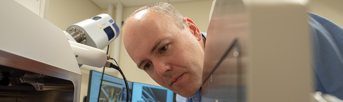 Matt White peers into an electron microscope in his lab