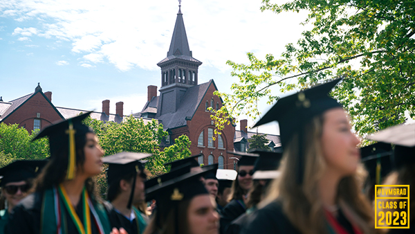 graduates wearing caps and gowns with old mill in the background