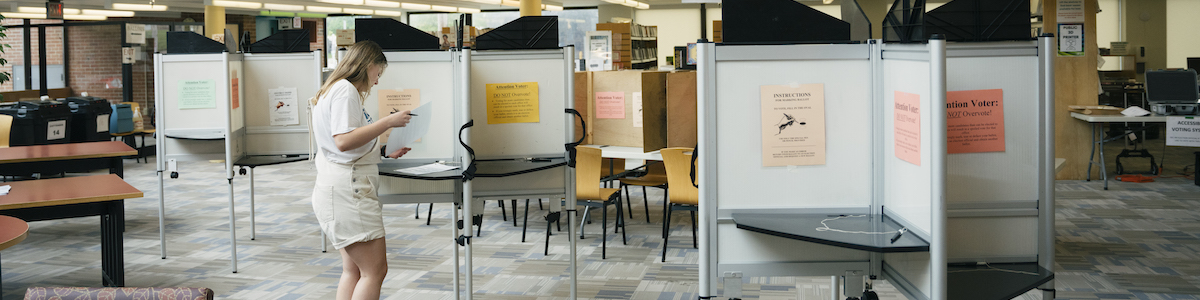 woman standing at a voting booth in a public library