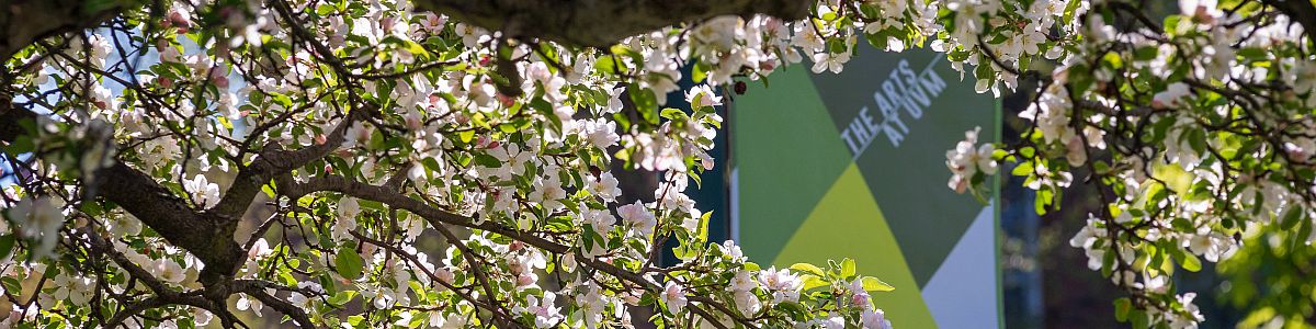 waterman building behind blooming trees showcasing arts at uvm banner 